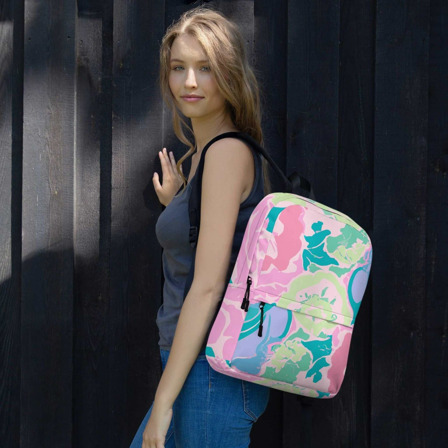 A pink floral backpack on the arms of a woman.