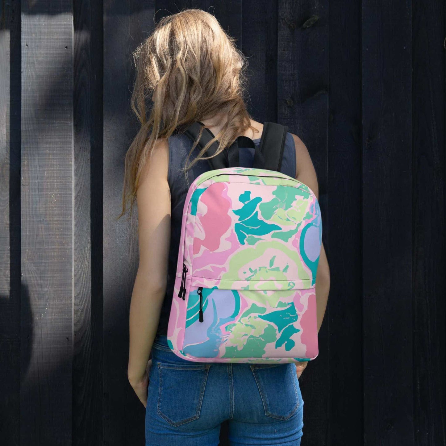 A pink floral backpack on the back of a woman. The back of the woman is facing the camera.