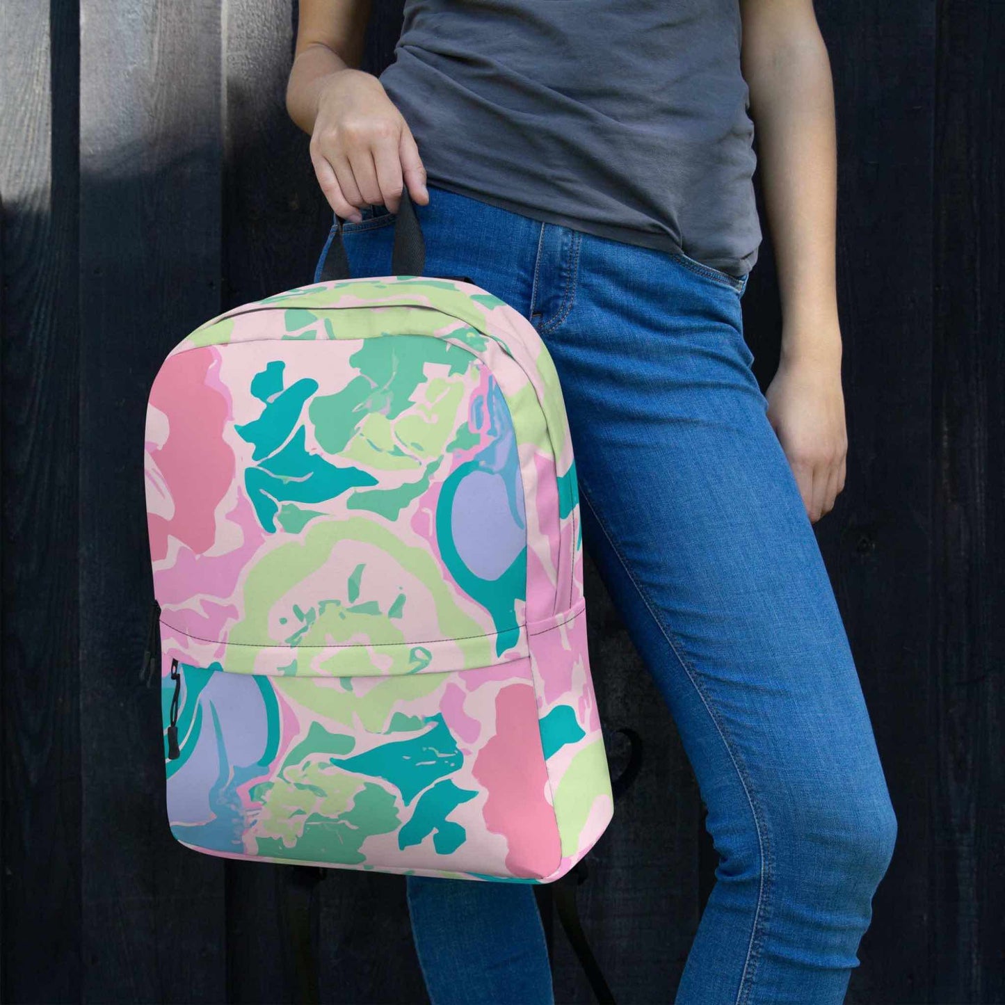 A pink floral backpack held by a woman.