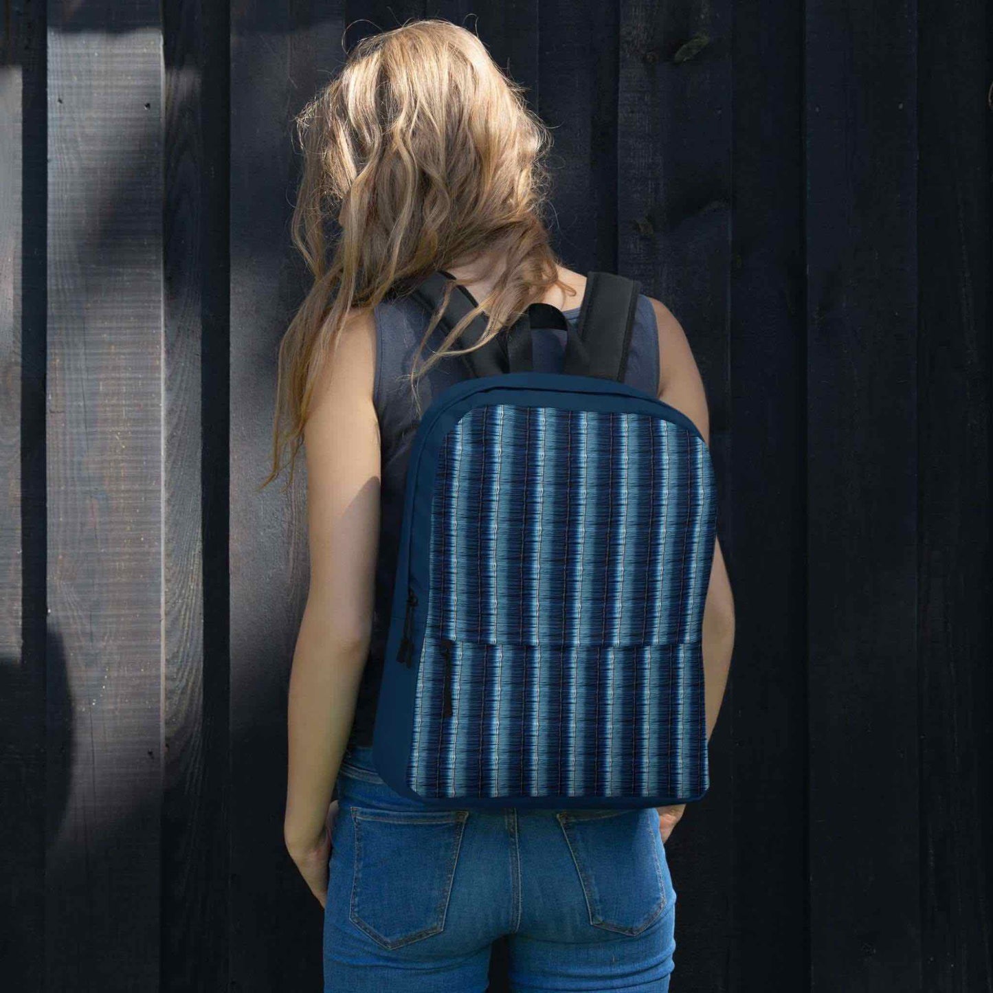 Printed backpack featuring denim stripes on the back of a woman. Back view of woman.