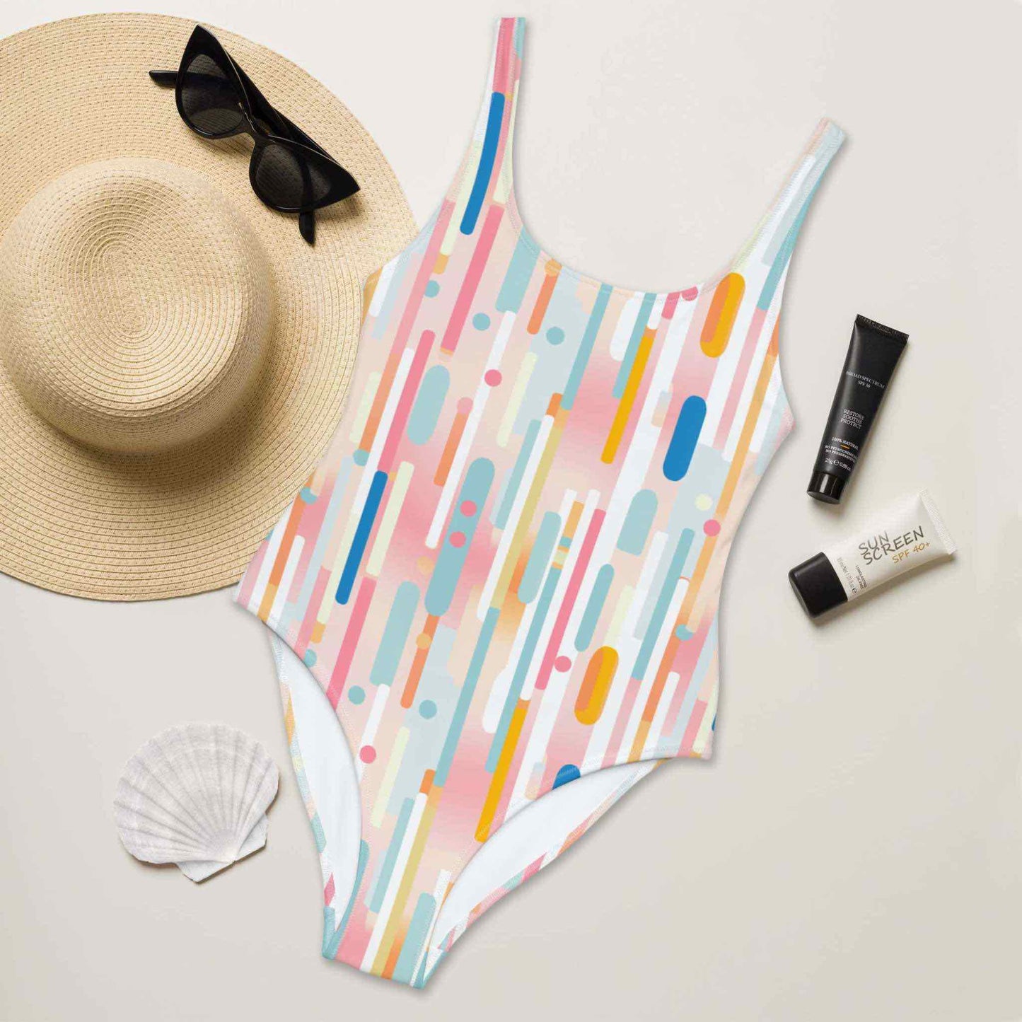 Flatlay of a candy cane swimsuit (one-piece), featuring vertical light candy color strips, front facing up, surrounded by a straw hat, sunglasses, sea shell and sun lotion.
