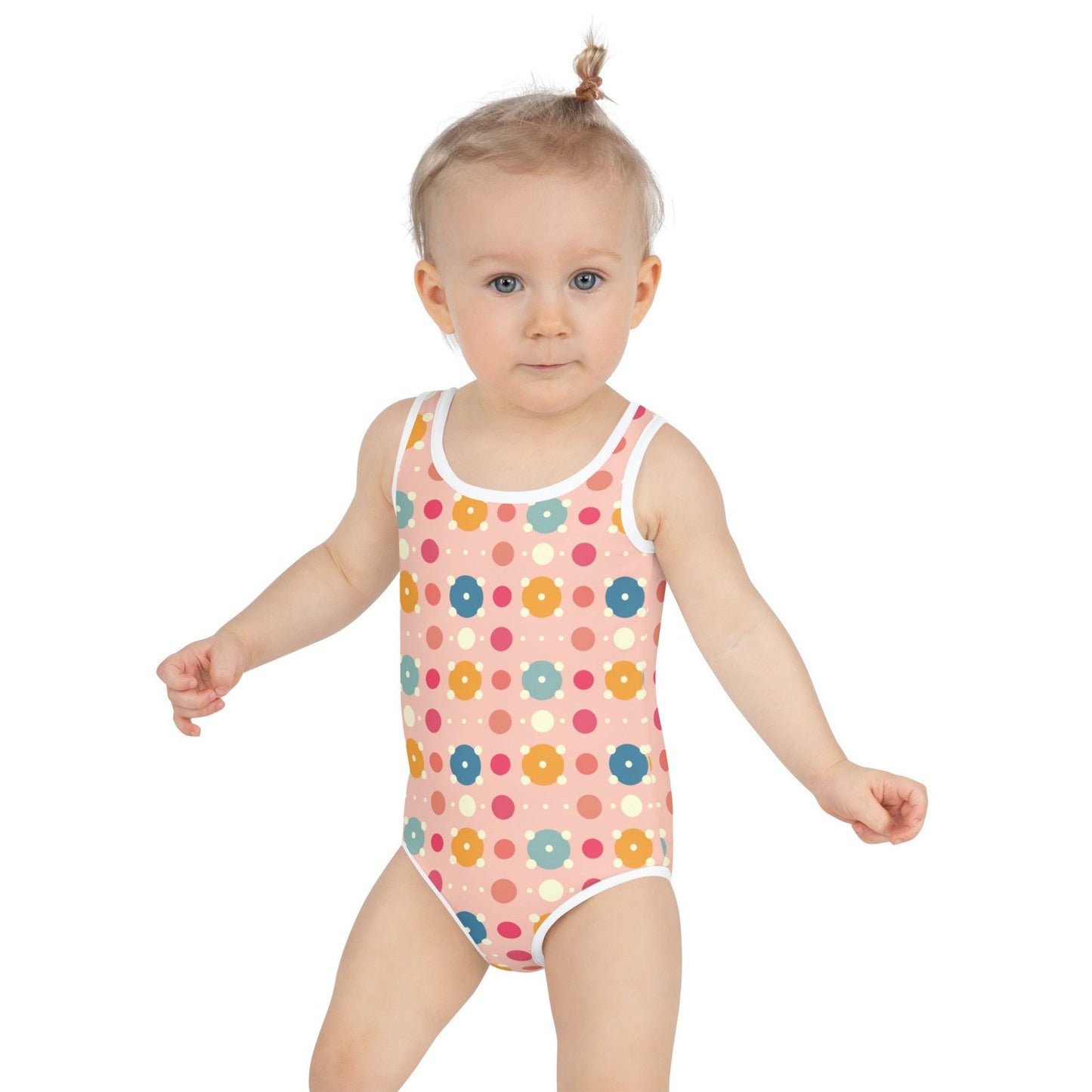Cute infant swimsuit, suitable for kids in general, features a playful pattern of pastel and white circles on a pink background, worn by an infant. White background.