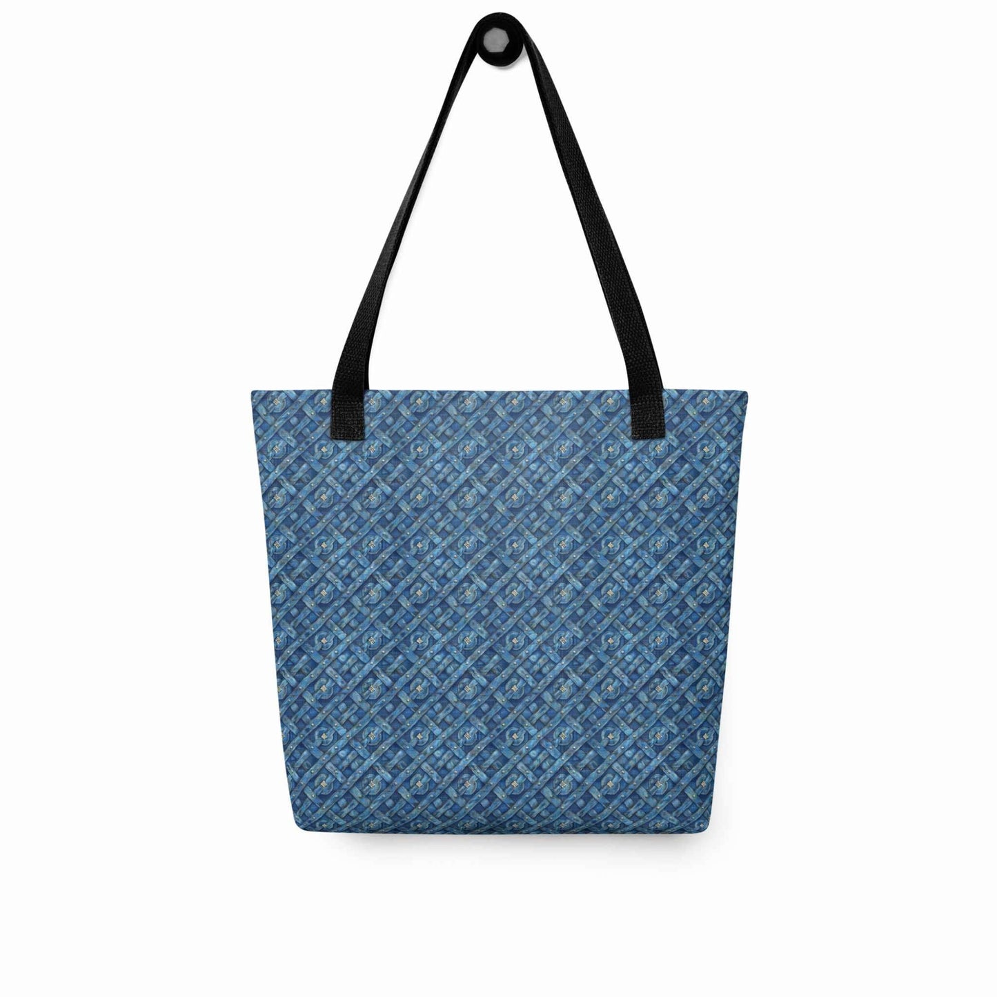 Blue tote bag with black handles, which features a blue Viking inspired denim pattern, hanging on a white wall. Dimension 15x15 inches.