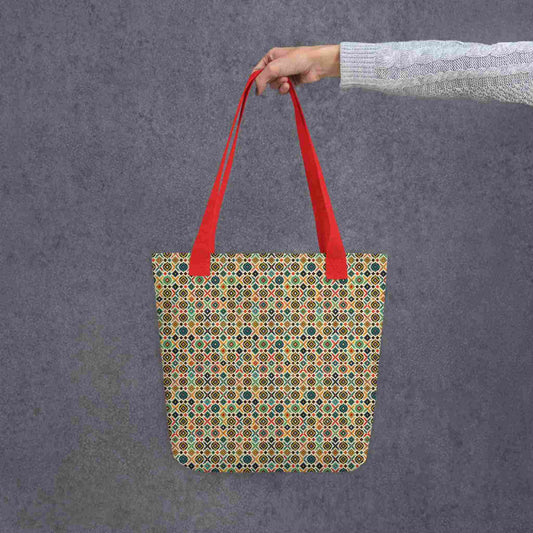 Rustic tote bag with red handles, which design is an Argentinian inspired diamond pattern, held by a lady's hand. Dimension 15x15 inches. Grey background.