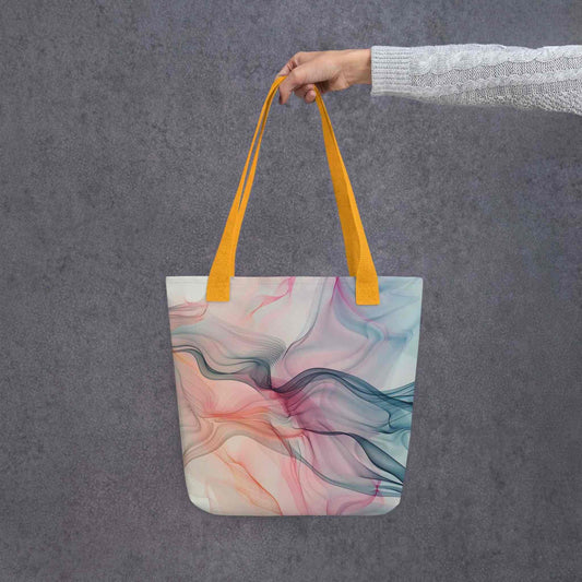 Fashion ladies tote bag with yellow handles, which design features an abstract art of artistic wavy bluish and pastel lines, held by a lady's hand. Dimension 15x15 inches. Grey background.