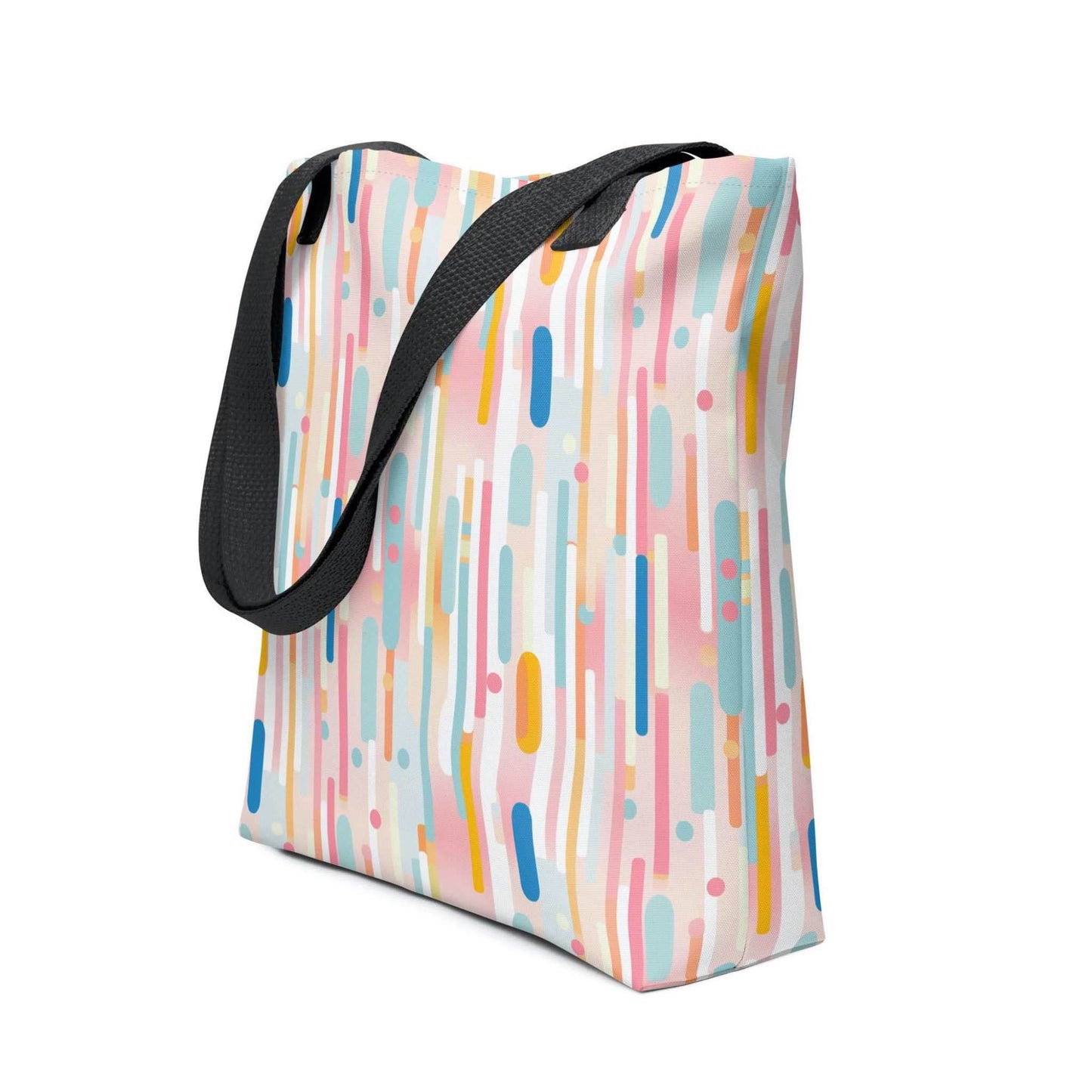 Light pink tote bag with black handles, which design is abstract vertical lines of pastel pink and other pastel shades, shown in side view. Dimension 15x15 inches. White background.