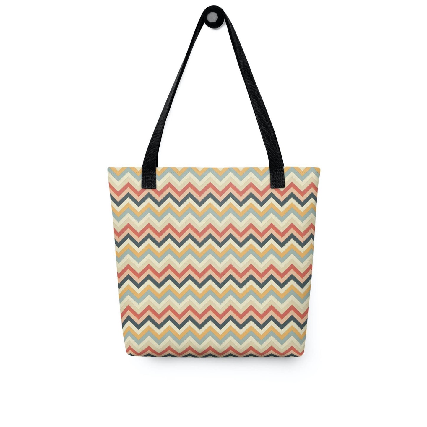 Zig zag tote bag with black handles, in a multicoloured pattern of Zig Zag lines, hanging on a white wall. Dimension 15x15 inches. White background.