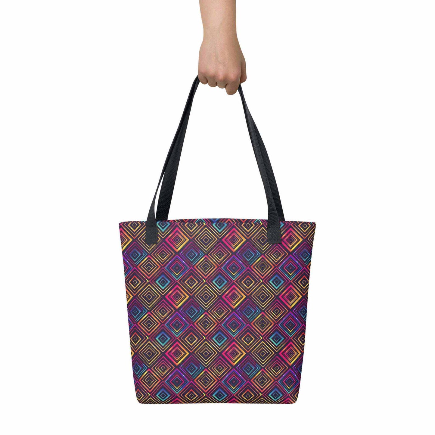 Fashion tote bag with black handles, which features a neon tapestry design in a sophisticated blend of colors, held in a hand. Dimension 15x15 inches. White background.