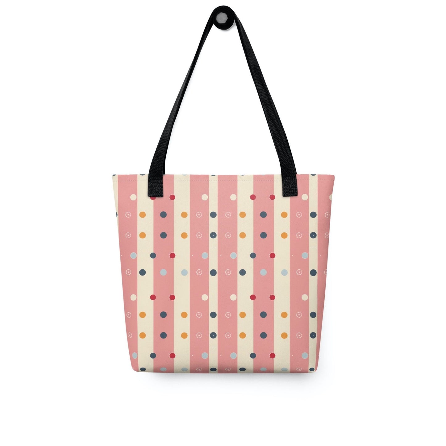 Pink striped tote bag with black handles, which features pink and beige stripes with colourful pokka dots, hanging on a white wall. Dimension 15x15 inches.