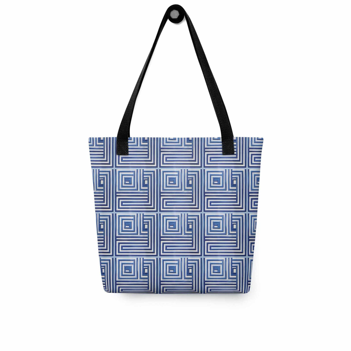 Blue op art tote with black handles, which features a blue op art illusion, hanging on a white wall.