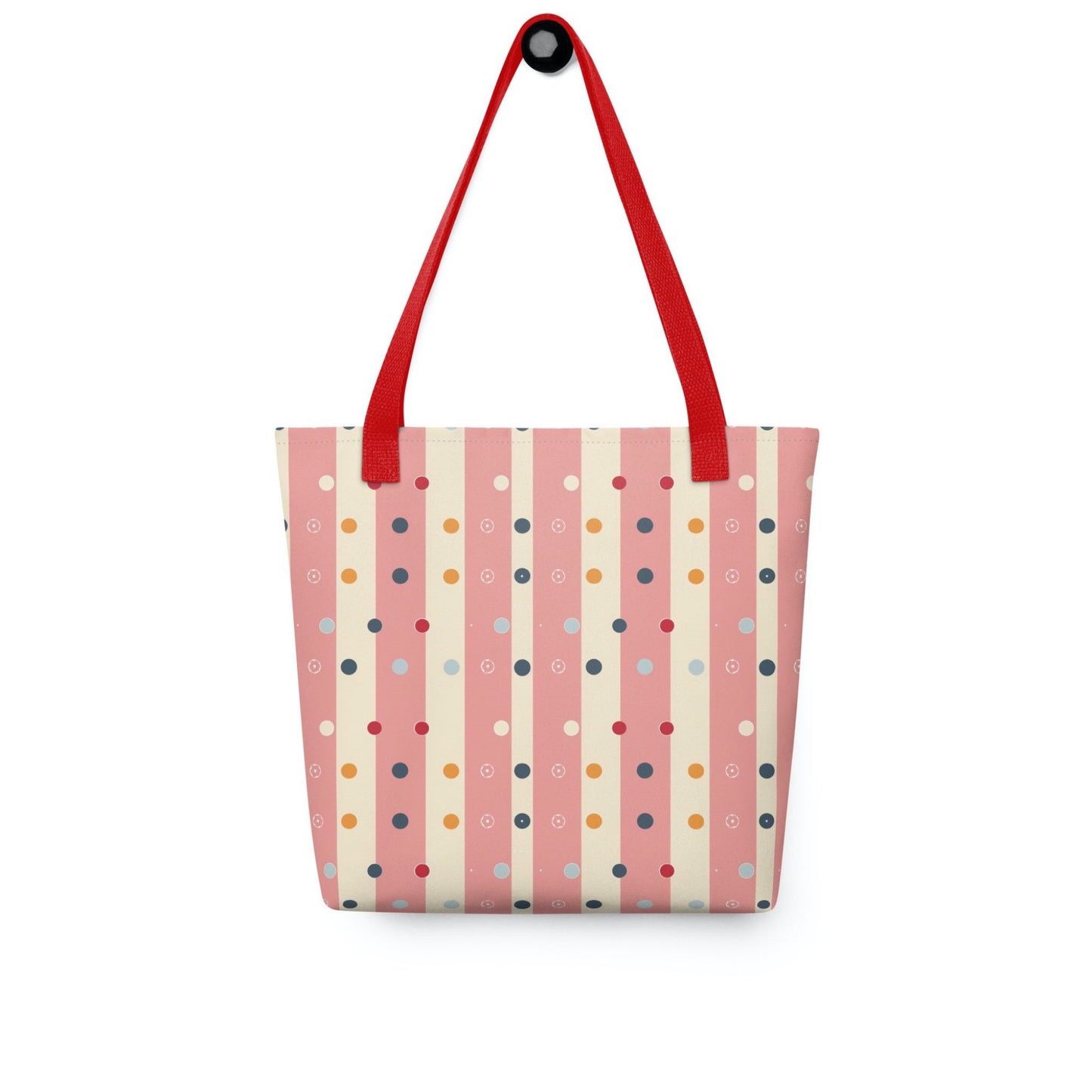 Pink striped tote bag with red handles, which features pink and beige stripes with colourful pokka dots, hanging on a white wall. Dimension 15x15 inches.
