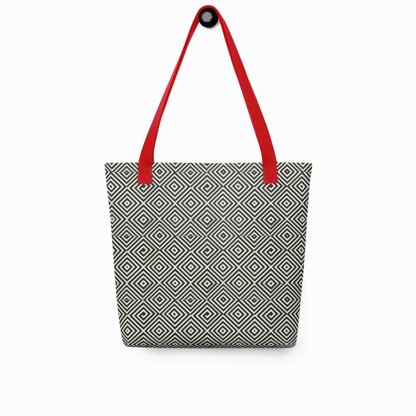 A diamond pattern tote bag with red handles, which features a mesmerizing black and white geometric look, hanging on a white wall.