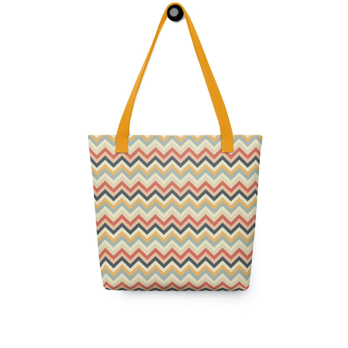Zig zag tote bag with yellow handles, in a multicoloured pattern of Zig Zag lines, hanging on a white wall. Dimension 15x15 inches. White background.