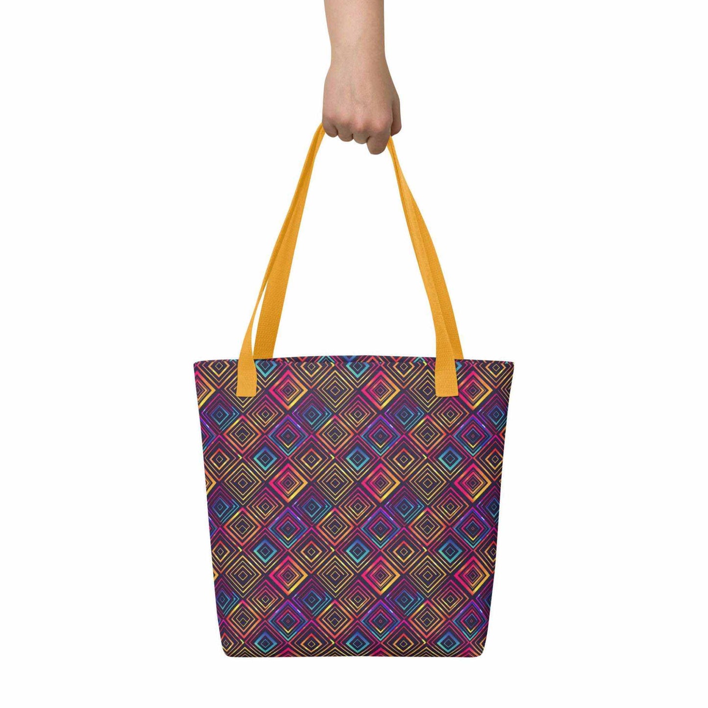 Fashion tote bag with yellow handles, which features a neon tapestry design in a sophisticated blend of colors, held in a hand. Dimension 15x15 inches. White background.