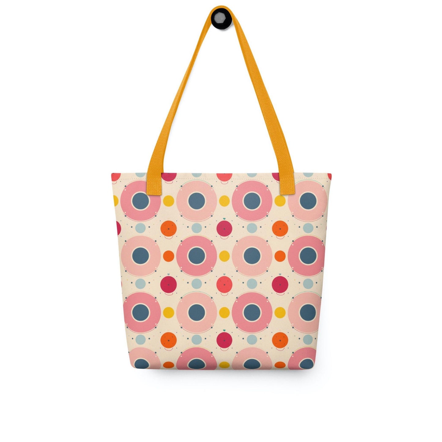 Artsy tote bag with yellow handles, which features an artsy design of pastel candy pops of color in a beige background, hanging on a white wall. Dimension 15x15 inches.