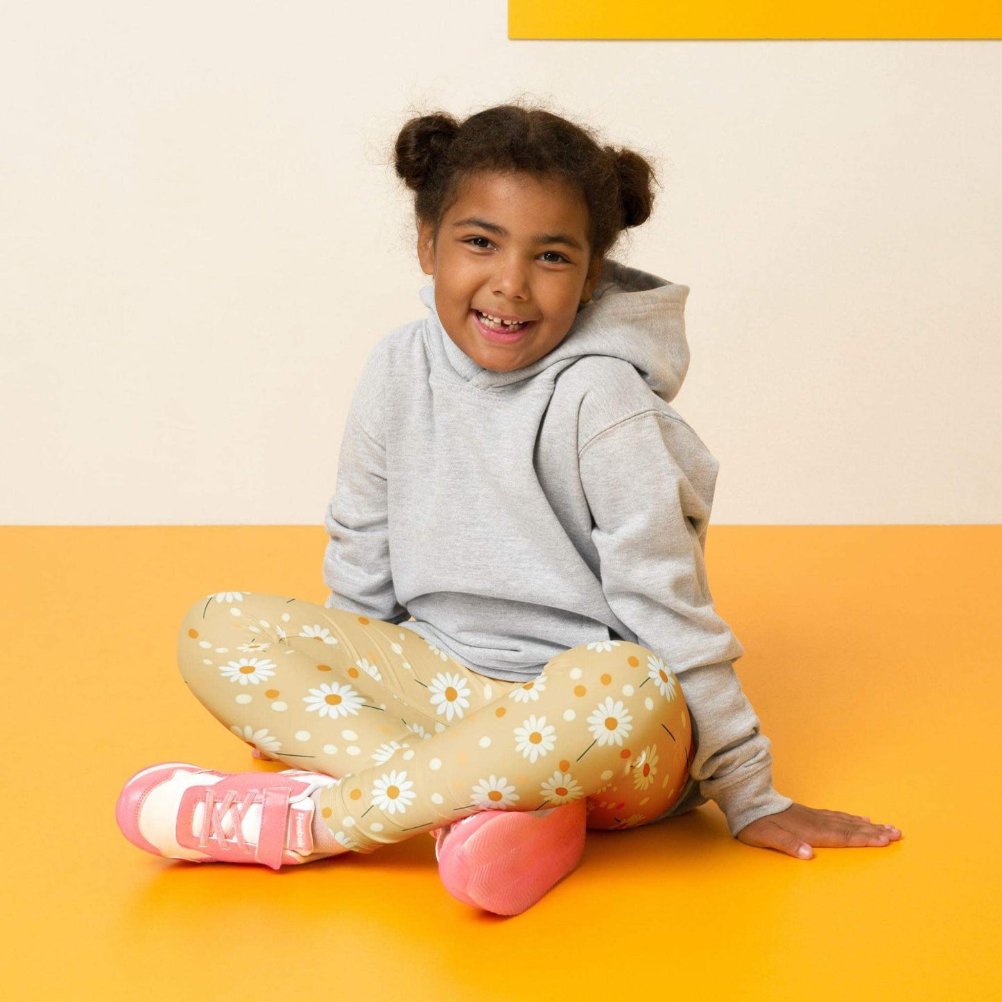 2T yellow leggings named DAISYDOODLE for toddlers, and bigger sizes for kids. This design features playful daisies &amp; polka dots on a bright egg yellow background, worn by a little girl / toddler, sitting on the floor against a cream and yellow background. 