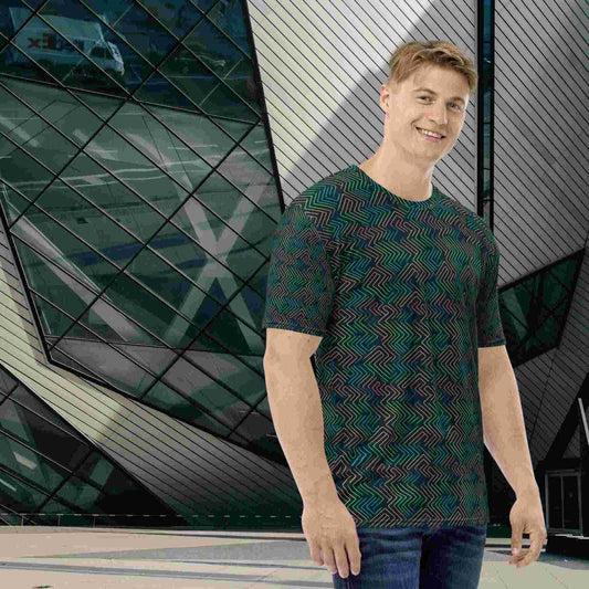 Caucasian male in an all-over-print T-shirt in a dark green neon pattern, standing in front of a modern and futuristic building.