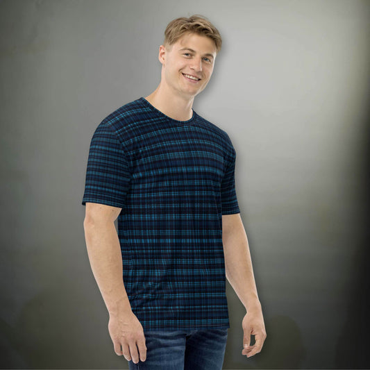 Male Caucasion in a plaid dark blue all-over-print tshirt, in a plaid design that blends modern structure with timeless charm, offering a sophisticated yet versatile look. The man stands in front of an illuminated dark grey wall.