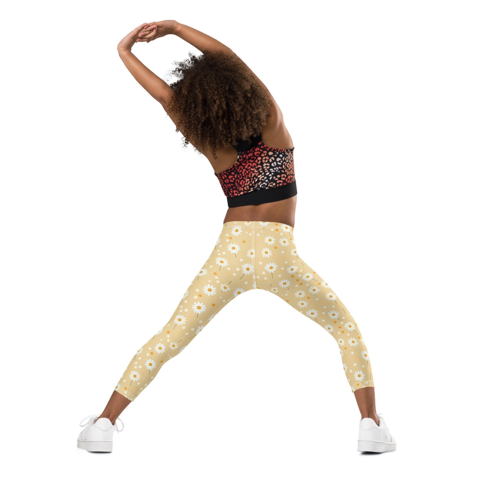 2T yellow leggings named DAISYDOODLE for toddlers, and bigger sizes for kids. This design features playful daisies &amp; polka dots on a bright egg yellow background, worn by a young girl, her back facing the camera. White background.