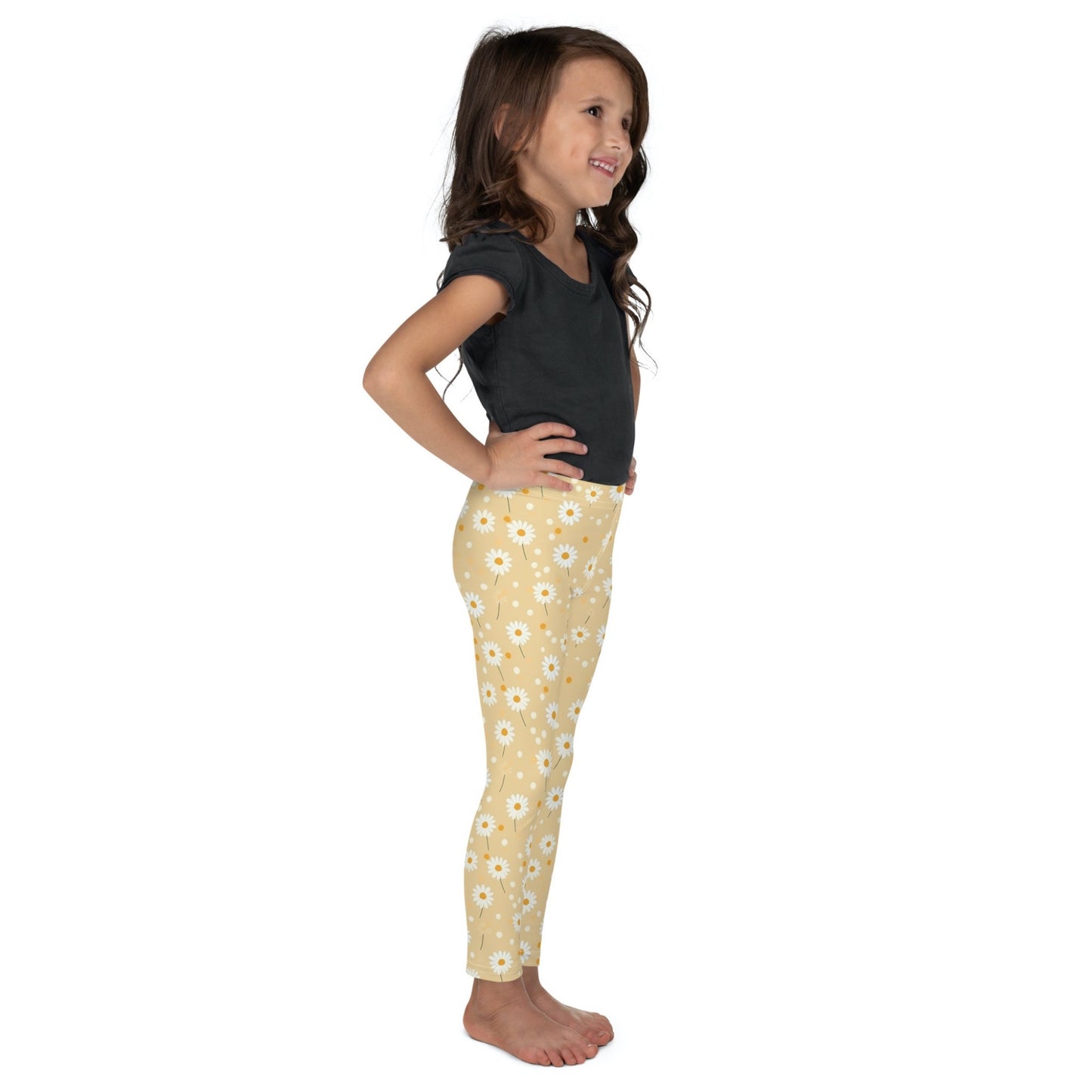 2T yellow leggings named DAISYDOODLE for toddlers, and bigger sizes for kids. This design features playful daisies &amp; polka dots on a bright egg yellow background, worn by a little girl, the right side of her body facing the camera. White background.