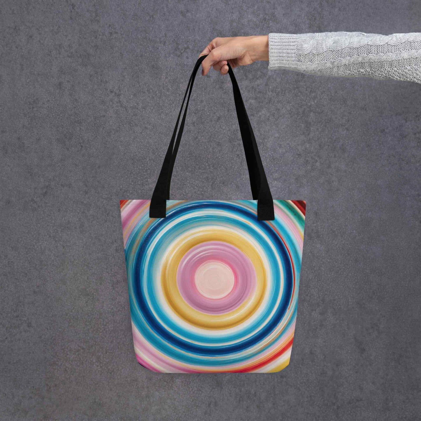 Colorful tote bag which features a mesmerizing abstract design of strong, hypnotic color circles, with black handles. Dimension 15x15 inches, polyester. Grey blackground. 