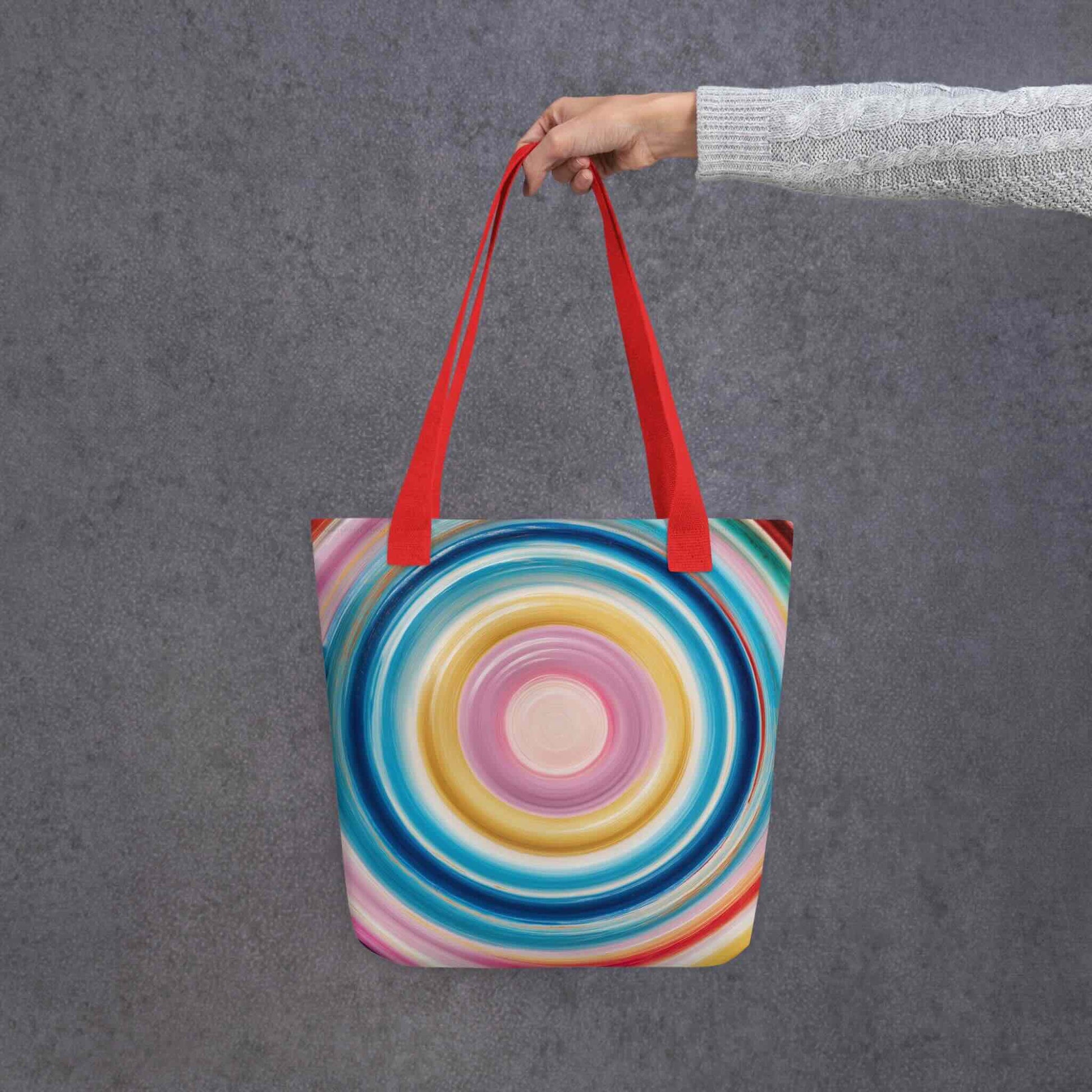 Colorful tote bag which features a mesmerizing abstract design of strong, hypnotic color circles, with red handles. Dimension 15x15 inches, polyester. Grey blackground. 