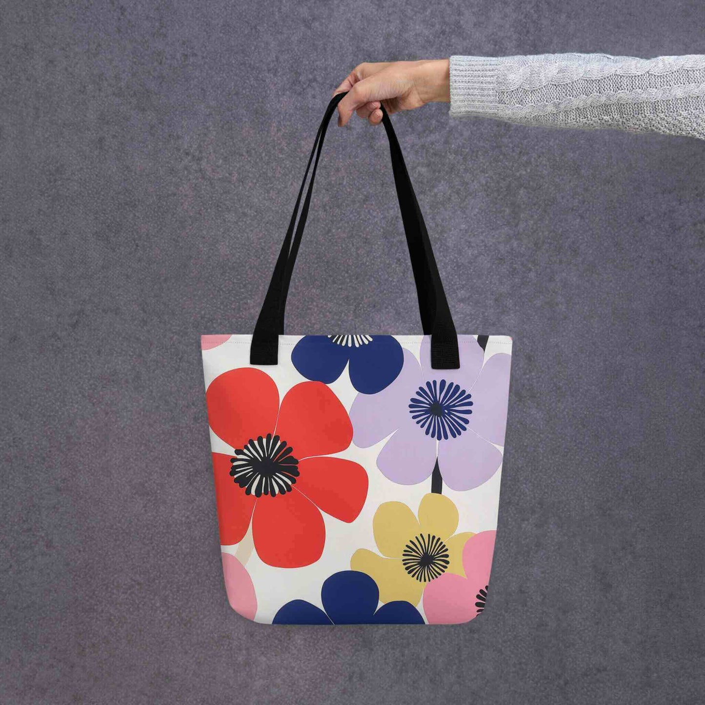 A Floral Tote Bag, with black handles, which features a stunning, abstract bloom pattern that brings warmth and joy wherever you go. Grey Background.