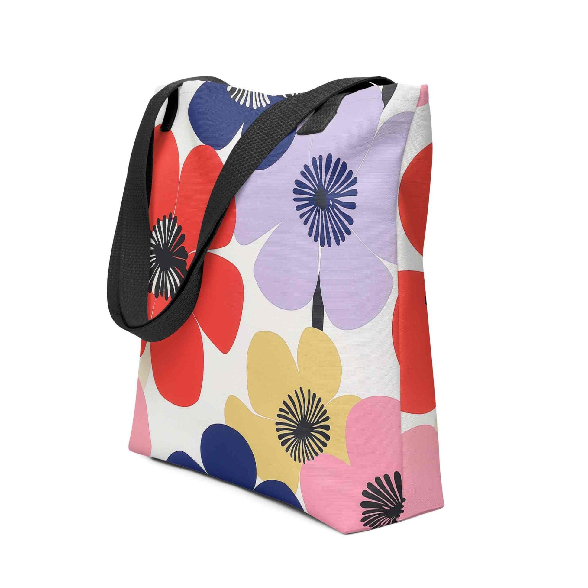 A Floral Tote Bag, with black handles, which features a stunning, abstract bloom pattern that brings warmth and joy wherever you go. Side View. White background.