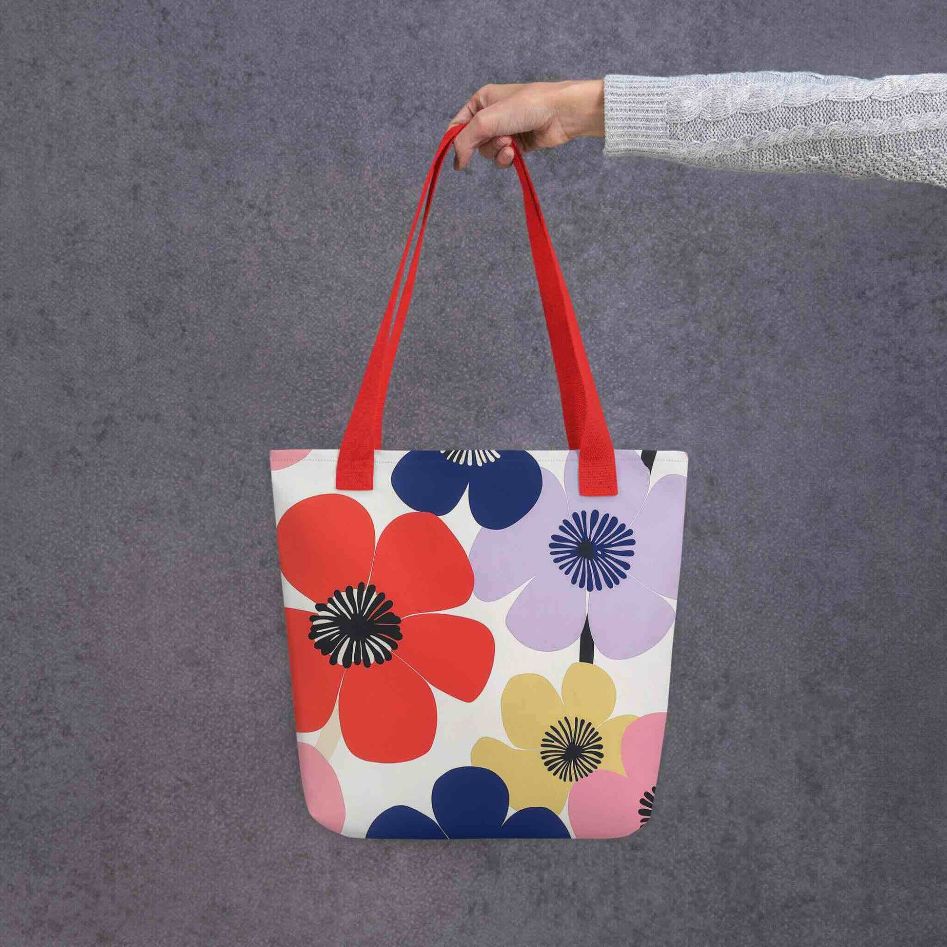 A Floral Tote Bag, with red handles, which features a stunning, abstract bloom pattern that brings warmth and joy wherever you go. Grey Background.