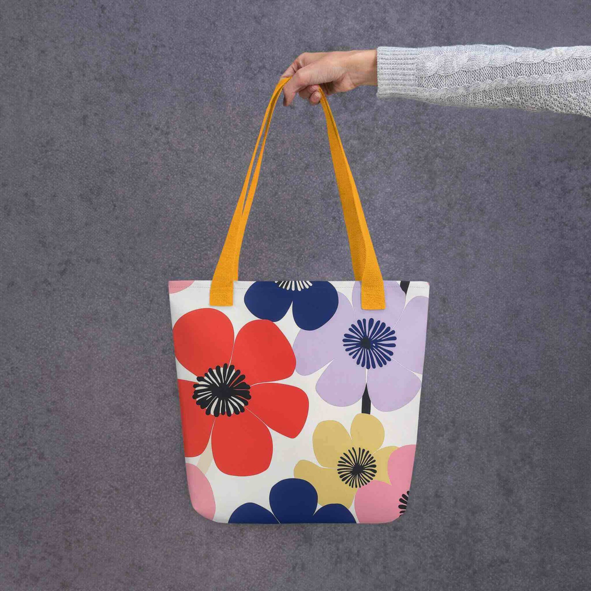 A Floral Tote Bag, with yellow handles, which features a stunning, abstract bloom pattern that brings warmth and joy wherever you go. Grey Background.