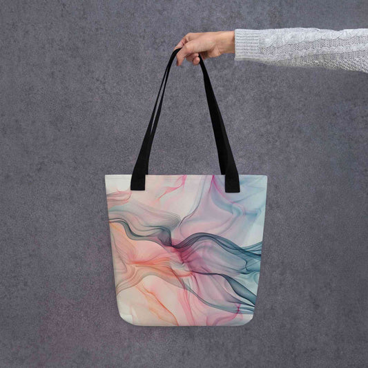 Fashion ladies tote bag with black handles, which design features an abstract art of artistic wavy bluish and pastel lines, held by a lady's hand. Dimension 15x15 inches. Grey background.