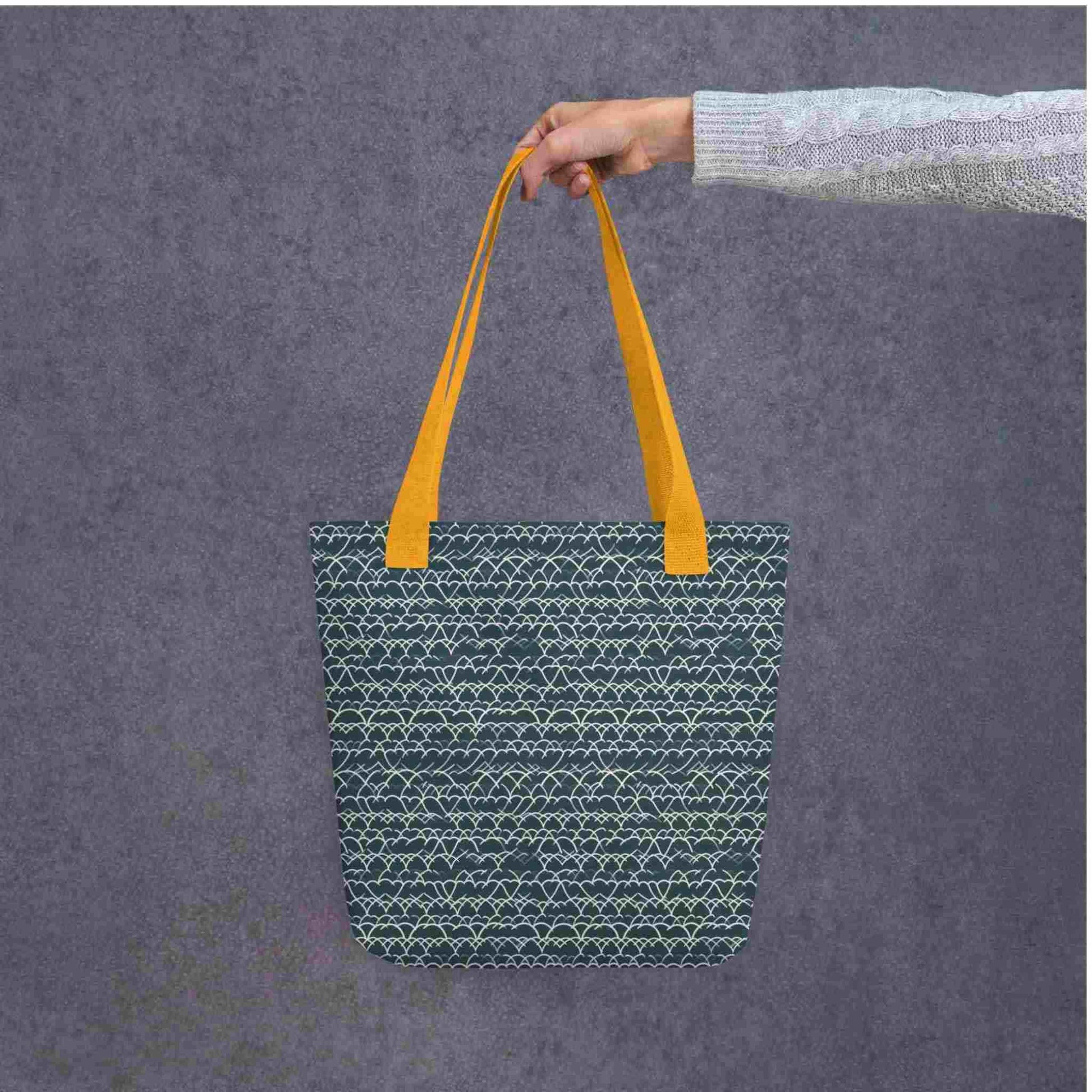 Blue Tote with White Geometric Lace with yellow handles, held by a lady's hand. Dimension 15x15 inches. Grey background.