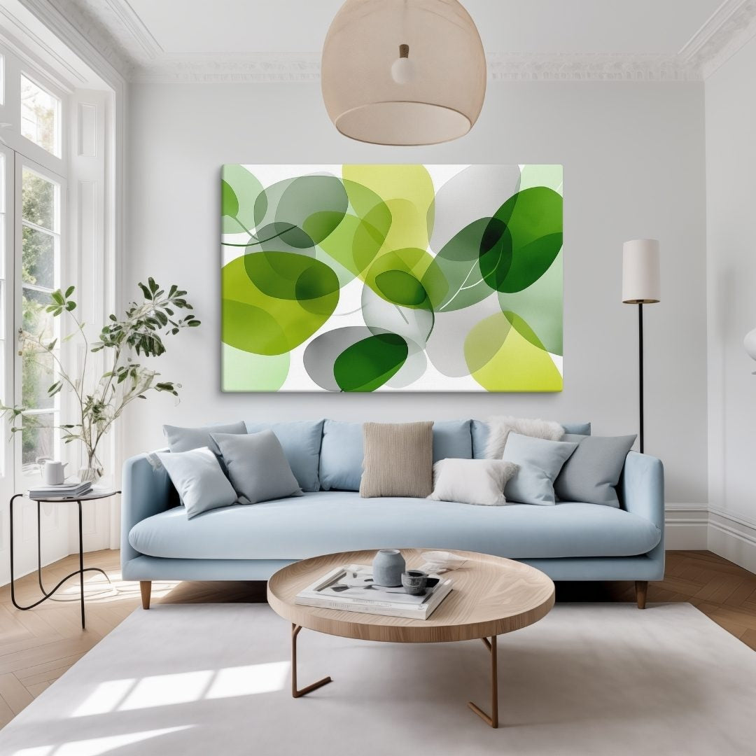 Illustration of a modern botanical artwork features layered, translucent green and chartreuse organic shapes for a lush, sophisticated feel on canvas, hanging in living room over a blue sofa.