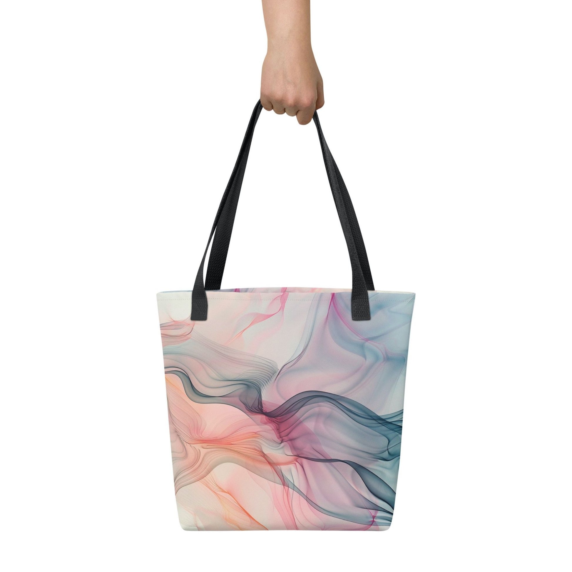 A 15x15 inch tote bag with black handles, which design is an abstract art of artistic wavy bluish and pastel lines, held by a lady's hand. White background.