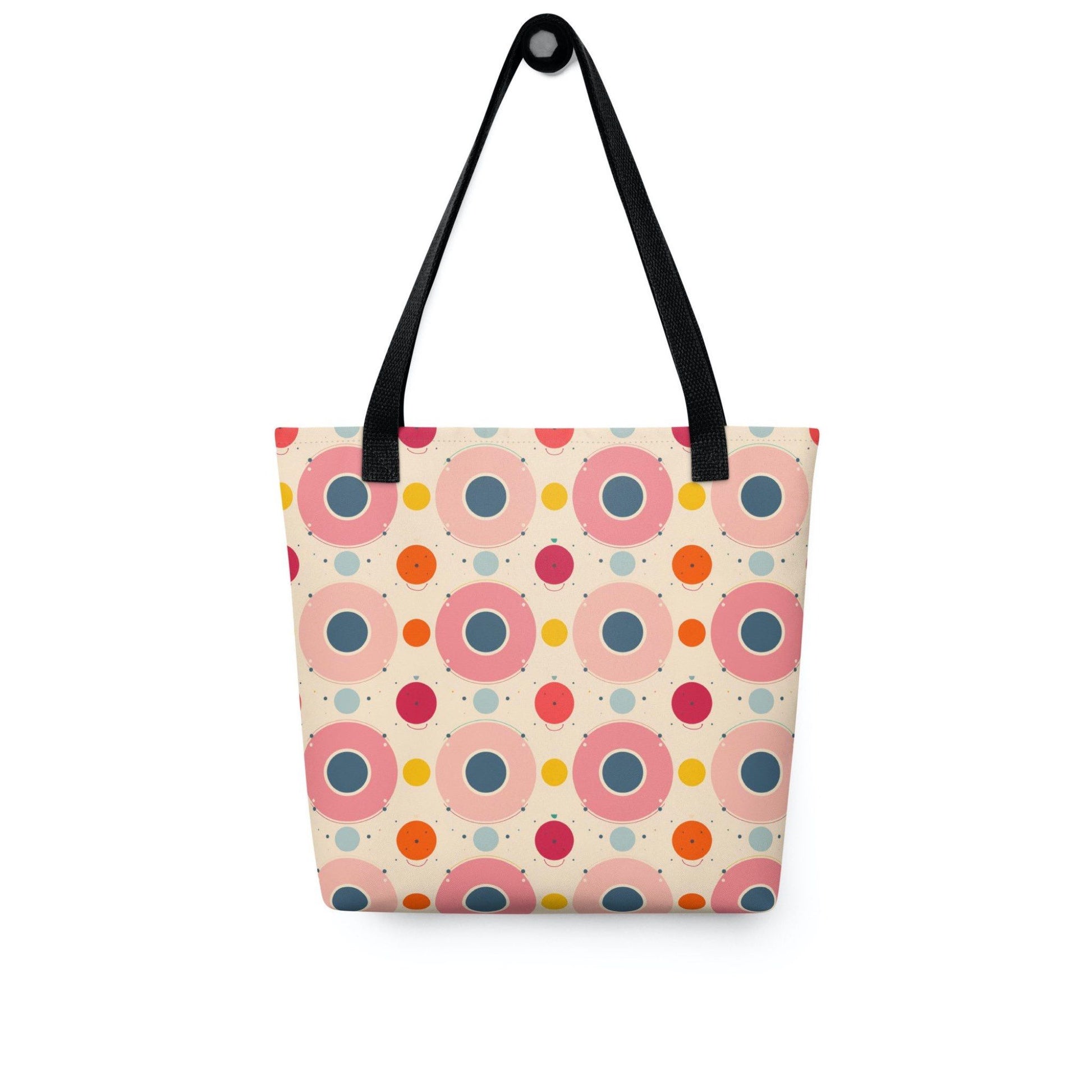 Artsy tote bag with black handles, which features an artsy design of pastel candy pops of color in a beige background, hanging on a white wall. Dimension 15x15 inches. 