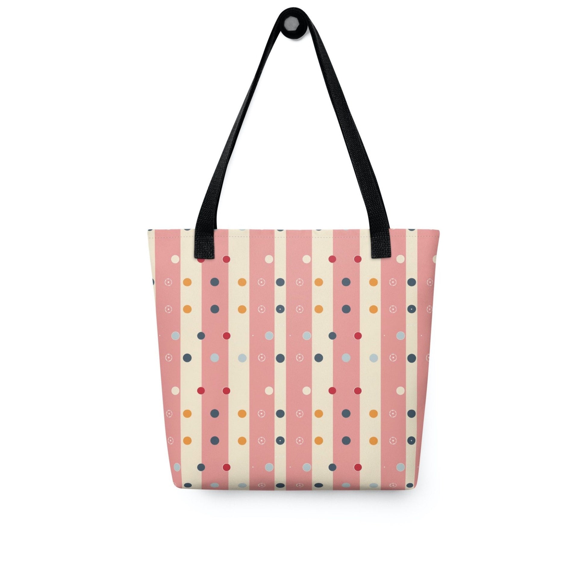 Pink striped tote bag with black handles, which features pink and beige stripes with colourful pokka dots, hanging on a white wall. Dimension 15x15 inches.