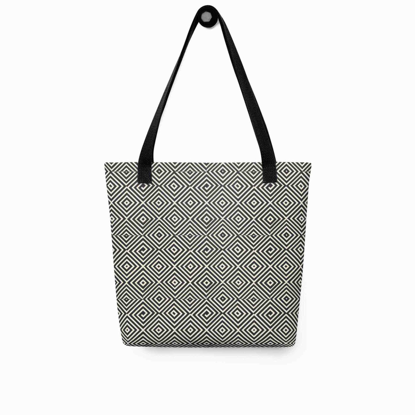 A diamond pattern tote bag with black handles, which features a mesmerizing black and white geometric look, hanging on a white wall.