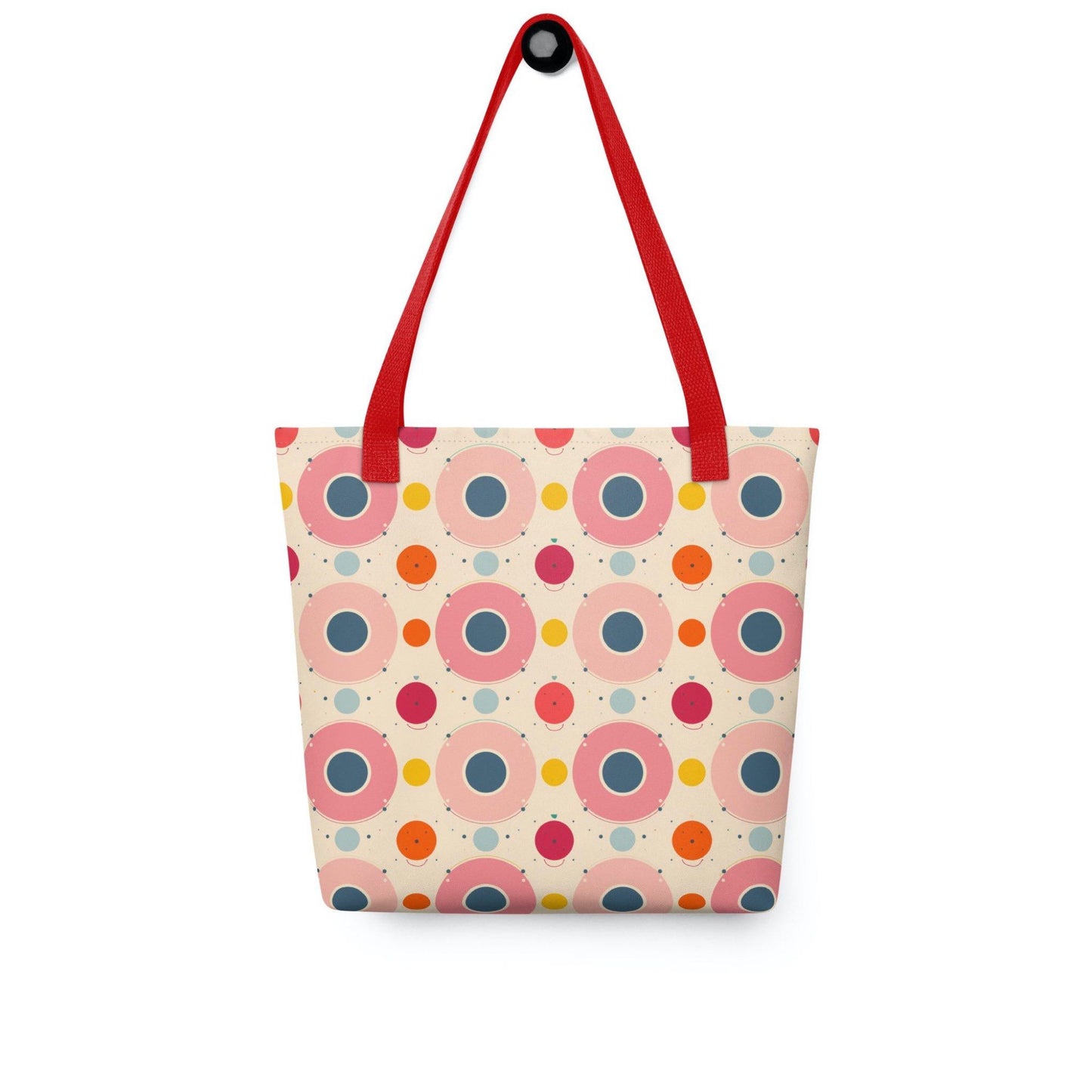 A 15x15 inch tote bag with red handles, which features an artsy design of pastel candy pops of colors in a beige background, hanging on a wall hook. White background.